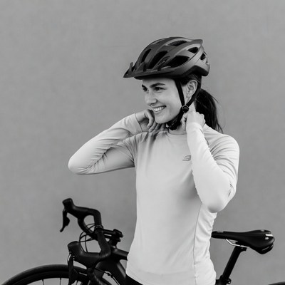 Woman adjusting helmet beside road bike