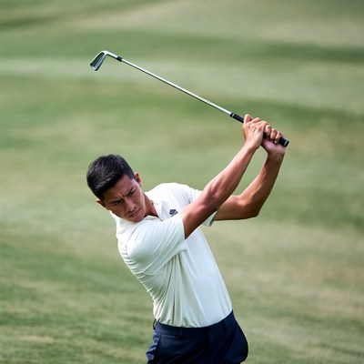 Asian man swinging golf club