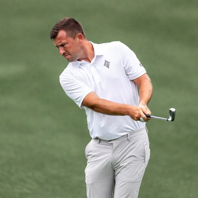 Man swinging golf club on green