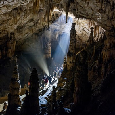 Tourists exploring cave with stalactites