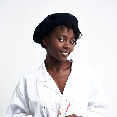 Black woman in beret and paint-splattered shirt