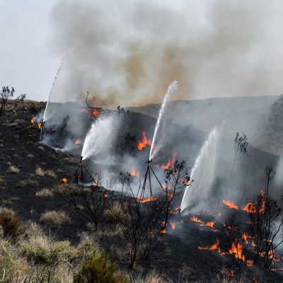 Firefighters spraying water on wildfire
