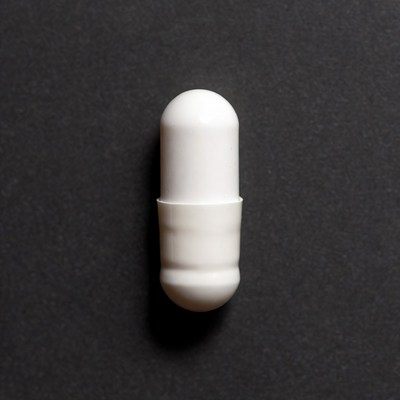 White capsule pill on black background