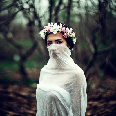 Woman in flower crown and white veil forest