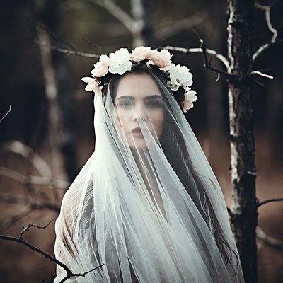 Woman in veil and flower crown in forest