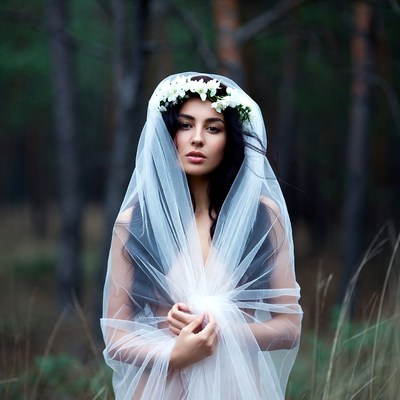 Bride in veil with flowers in forest