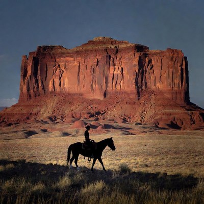Cowboy riding horse near red rock mesa
