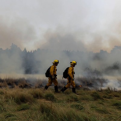 Two firefighters walking through wildfire smoke