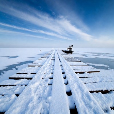 Snowy Wooden Pier with Chair on Frozen Lake
