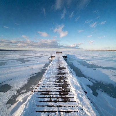 Wooden pier extending over frozen lake