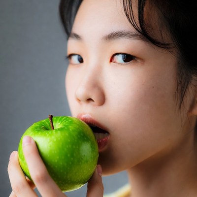 Asian woman biting green apple