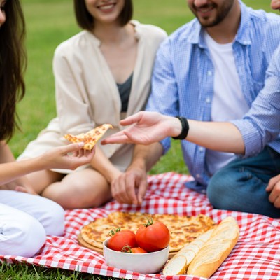 Friends sharing pizza picnic outdoors