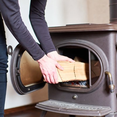 Man loading firewood into wood stove