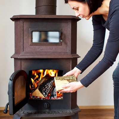 Woman adding firewood to wood stove