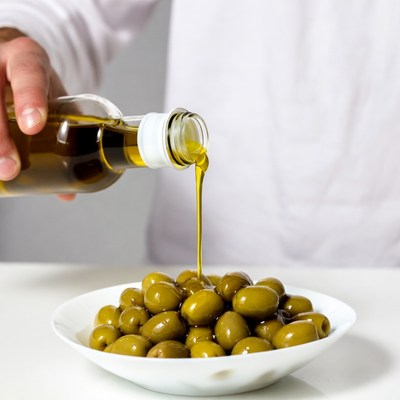 Chef pouring oil on olives