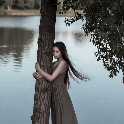 Woman hugging tree by lake