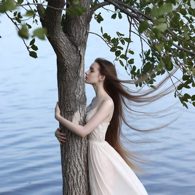 Woman hugging tree by lake
