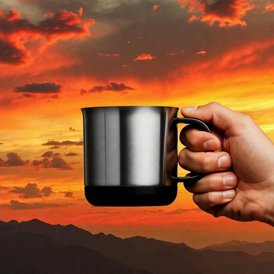 Hand holding mug against sunset mountains