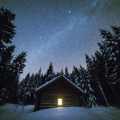 Log cabin glowing under starry sky