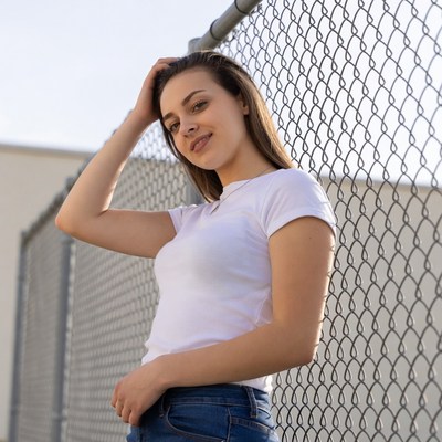 Young woman leaning on chain link fence