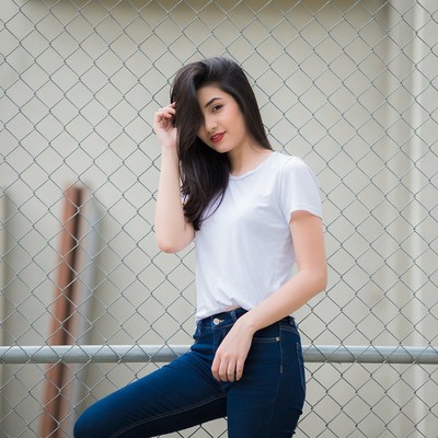 Asian woman posing by chain-link fence