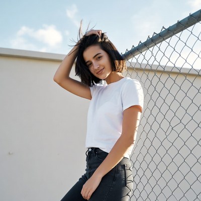Young woman leaning on chain link fence