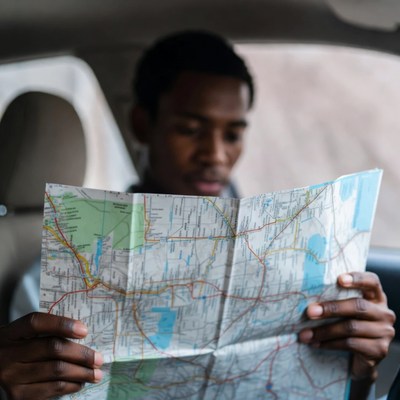 African-American man reading map in car