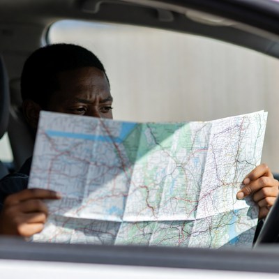 African-American man reading map in car