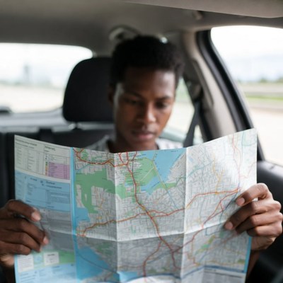 African-American man reading map in car