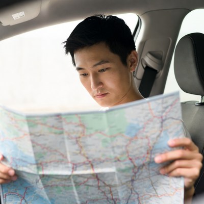 Asian man reading map in car