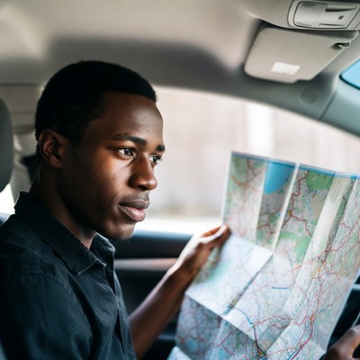 African-American man reading map in car