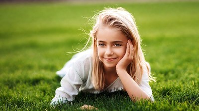 Blonde girl smiling on green grass