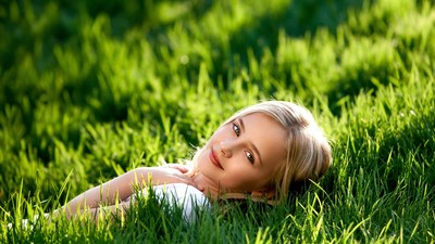 Blonde girl lying in green grass