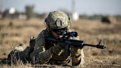 Soldier aiming rifle prone in desert