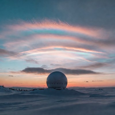 Radar Dome with Iridescent Clouds in Snowy Landscape