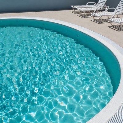Empty turquoise pool with lounge chairs