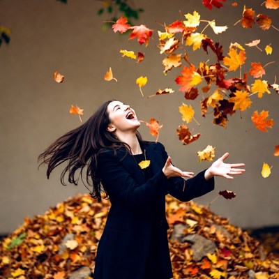 Woman laughing amid falling autumn leaves