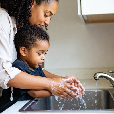 African-American mother helping toddler wash hands