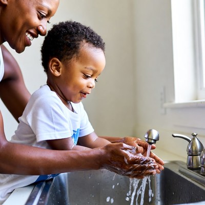 African-American mother helping toddler wash hands