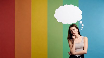 Woman thinking against rainbow wall
