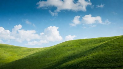 Green rolling hills under blue sky