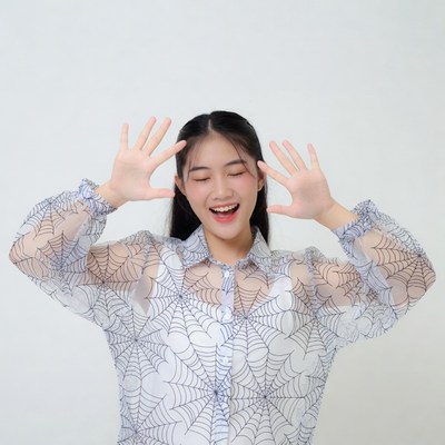 Asian woman in spiderweb shirt making excited gesture