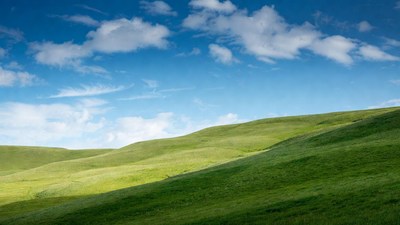 Green rolling hills under blue sky