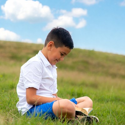 Young boy reading book outdoors