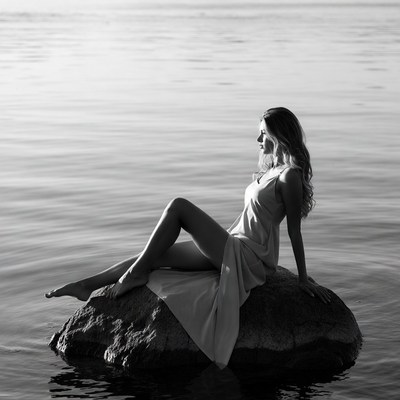 Woman sitting on rock by lake