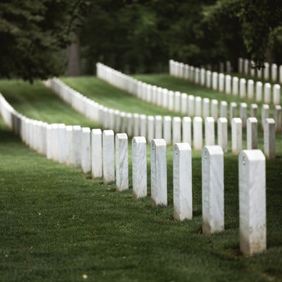 Rows of White Headstones in Grassy Cemetery