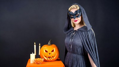 Blonde woman in witch mask with jack-o-lantern