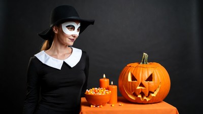Woman in witch mask with jack-o-lantern