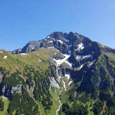 Snow-capped mountain peak with green slopes