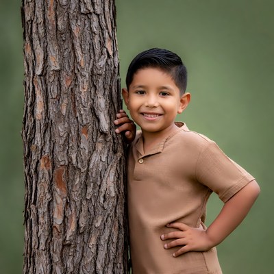 Boy smiling beside tree